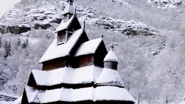 Cabana veche scandinavă acoperită cu zăpadă, în peisaj de iarnă montan.