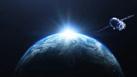 Satelit în orbită, iluminat de razele soarelui, peste Pământ.