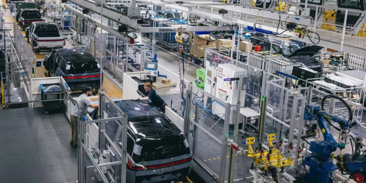 O fabrică modernă cu roboți și muncitori asamblând vehicule electrice.