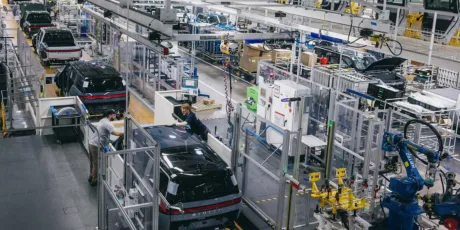 O fabrică modernă cu roboți și muncitori asamblând vehicule electrice.
