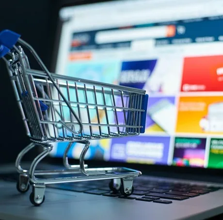 Carucior de cumpărături pe un laptop, simbolizând comerțul online.