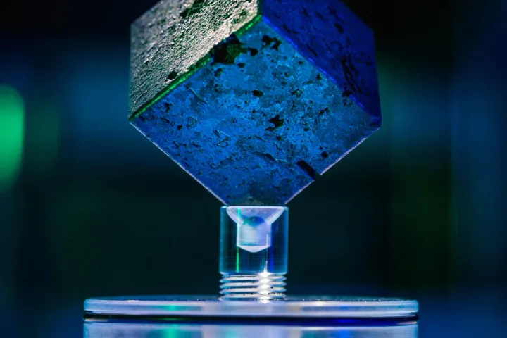 Un cub albastru plutind deasupra unei baze transparente, simbolizând cercetarea nucleară.