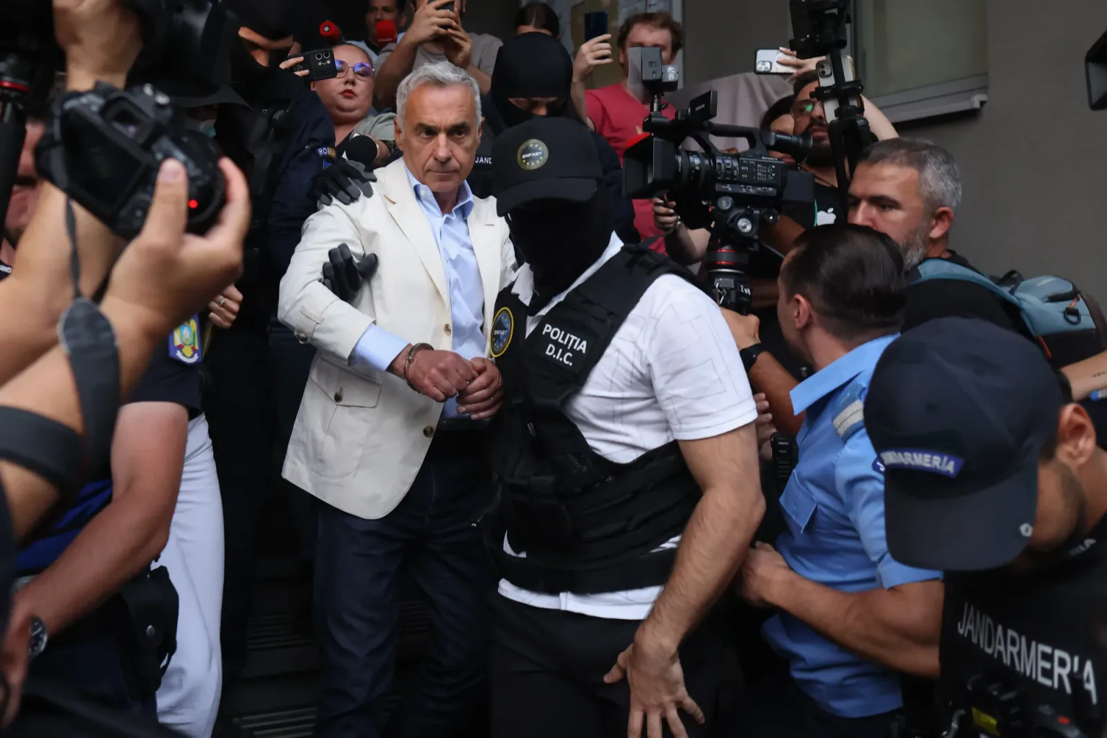 Călin Georgescu escortat de polițiști în fața instanței.