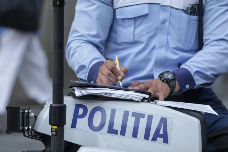 Un agent de poliție completează un proces-verbal pe o motocicletă de poliție.