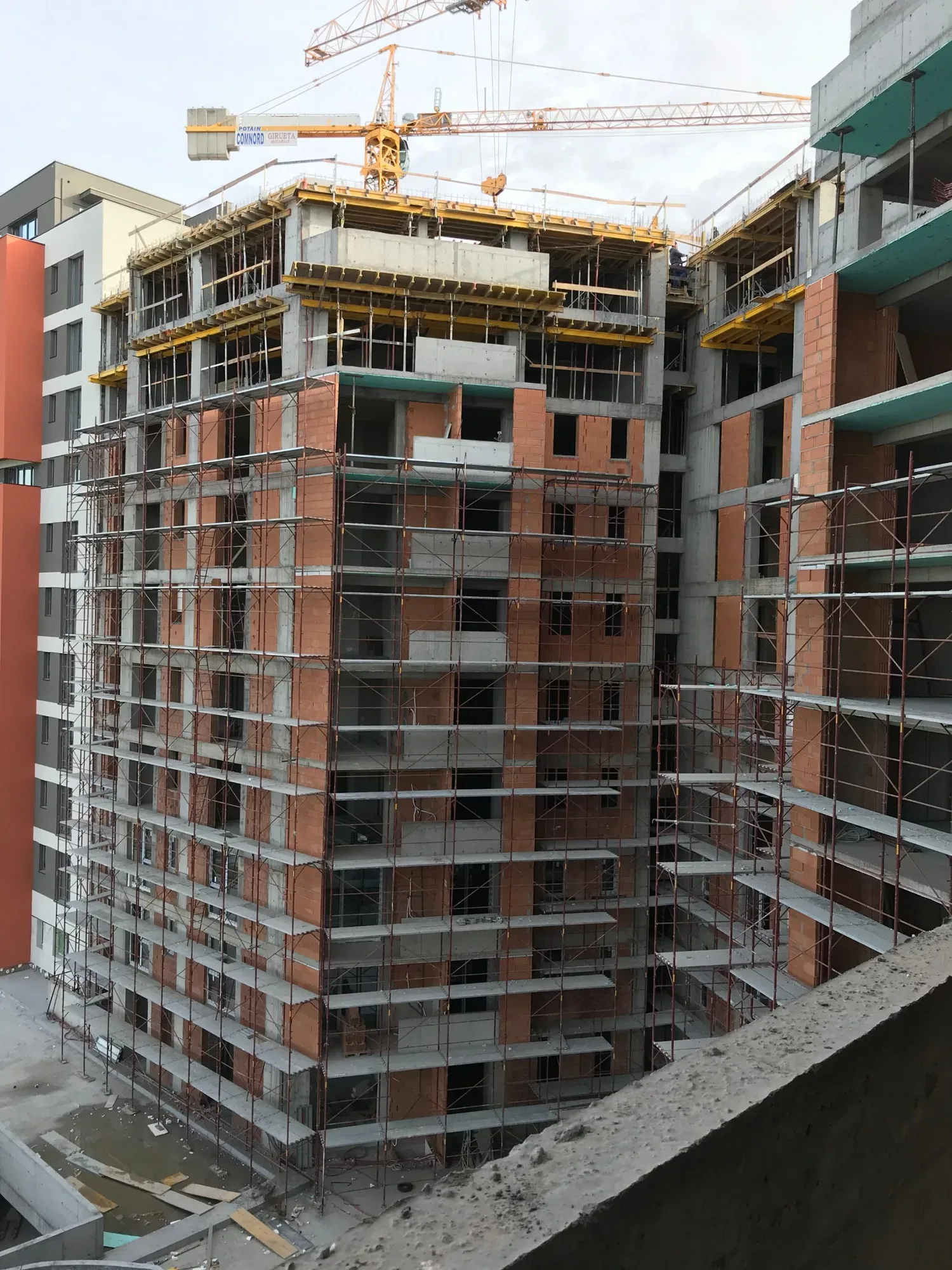 Construcție de locuințe noi în București, cu schele și utilaje vizibile.