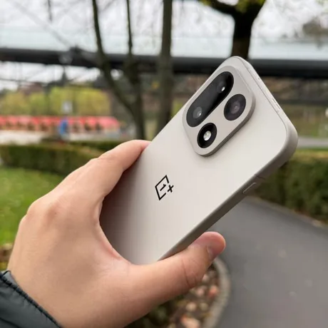 Un smartphone OnePlus 16, cu un design elegant, în mână, pe fundal verde.
