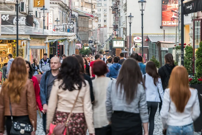 Oameni pe o stradă aglomerată din București, reflectând diversitatea urbană.