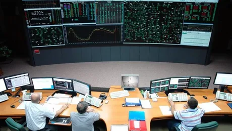 Persoane lucrând la calculatoare într-un centru de control energetic.