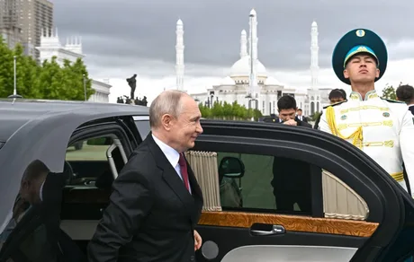 Vladimir Putin părăsește o mașină oficială, înconjurat de securitate.