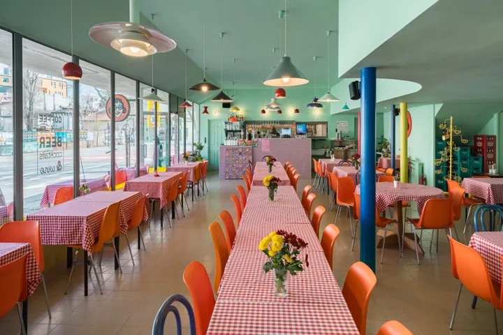 Interior modern al unui restaurant cu mese colorate și flori pe mese.