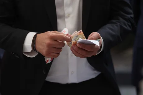 Bărbat numărând bancnote într-un mediu formal.