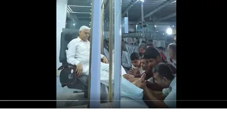 Liderul spiritual primește adepți dintr-o cabină de sticlă, protejat de căldură.