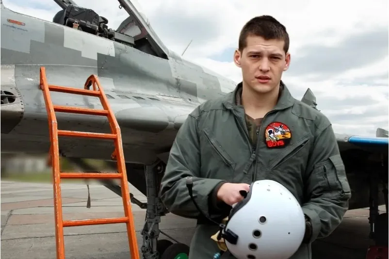 Pilot în fața unui avion de vânătoare, pregătit pentru misiune.
