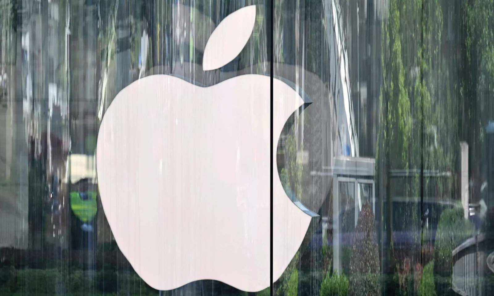 Logo-ul Apple reflectat pe o suprafață de sticlă, simbol al inovației tehnologice.