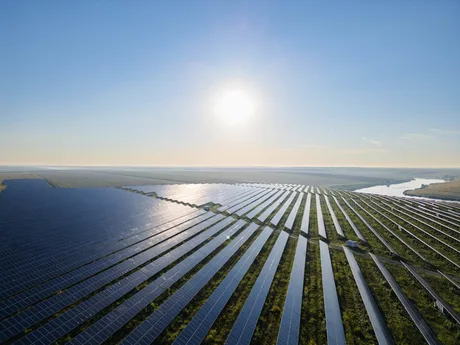 Panouri fotovoltaice amplasate pe un teren vast, sub un cer senin.