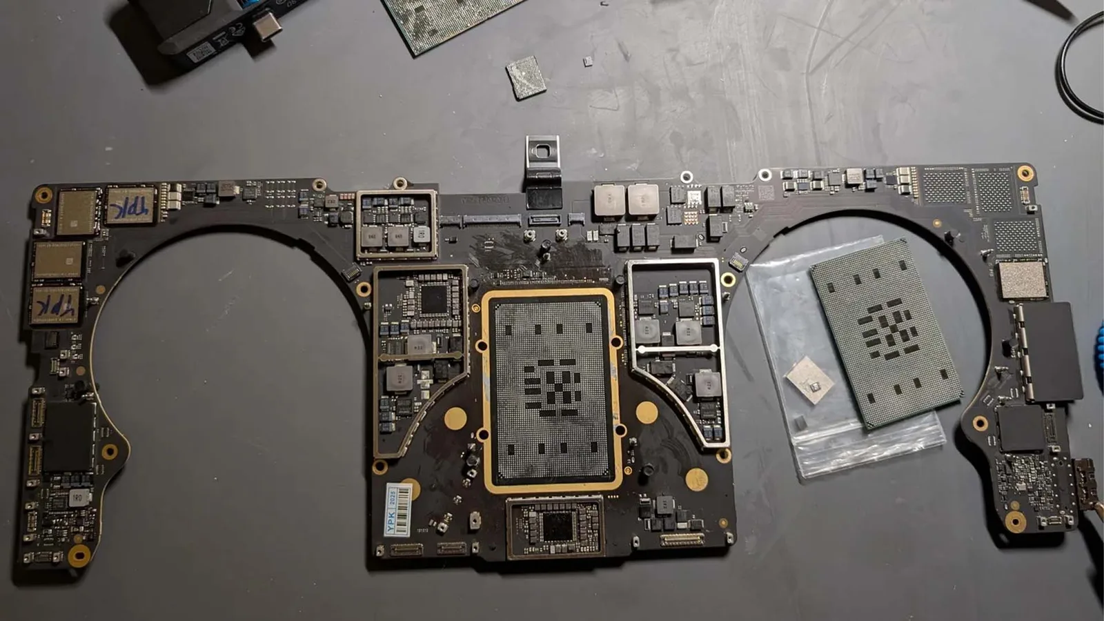 Placă de bază Apple cu componente electronice expuse pe un fundal de lucru.