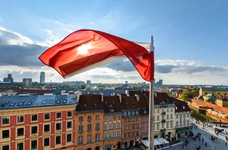 Steagul Poloniei fluturând deasupra clădirilor istorice din Varșovia.
