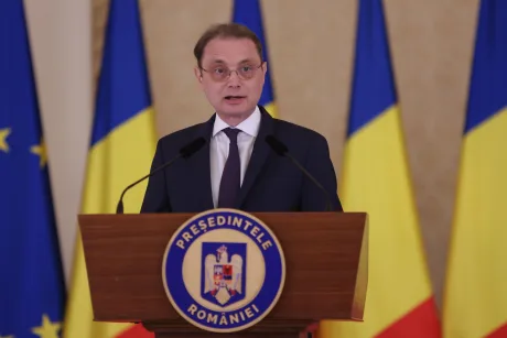 Luca Niculescu susține o conferință de presă în fața drapelului României.