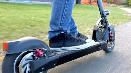Trotinetă electrică pe un drum, utilizată de o persoană.