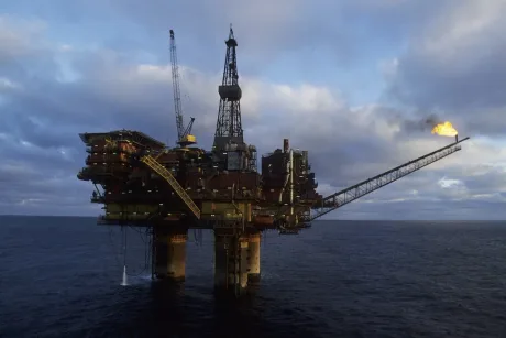 Platformă de extracție petrolieră în mare, cu flacără vizibilă.