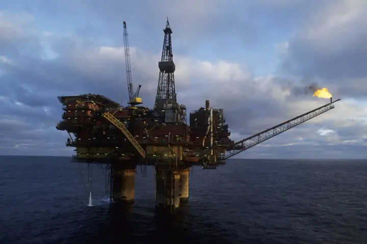 Platformă de extracție petrolieră în mare, cu flacără vizibilă.