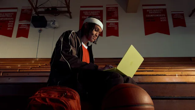 Elev lucrând pe MacBook Neo într-o sală de sport.