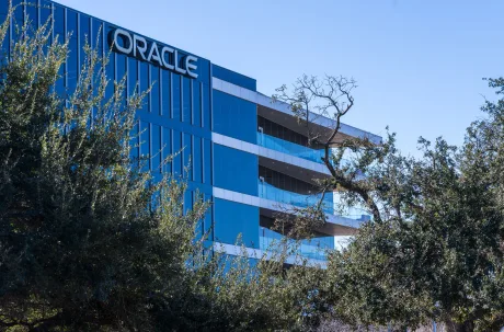 Clădirea Oracle înconjurată de copaci verzi, sub un cer senin.