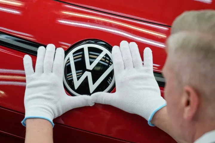 Logo Volkswagen aplicat pe un vehicul roșu în cadrul unei uzine.