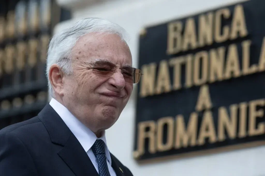 Un bărbat în costum lângă sediul BNR, expresie serioasă.