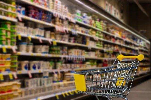 Raft cu produse alimentare într-un magazin, evidențiind prețurile în creștere.