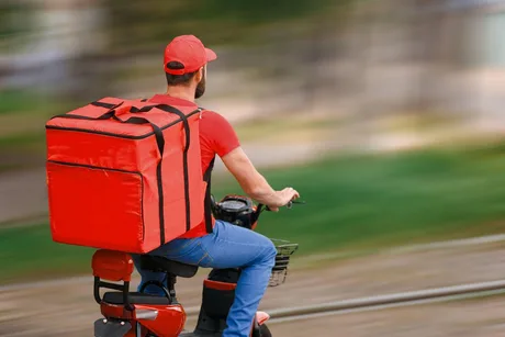 Livrator de hrană pe bicicletă, transportând produse alimentare.