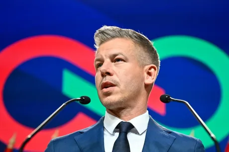 Peter Magyar vorbește la o conferință, cu fundal colorat.