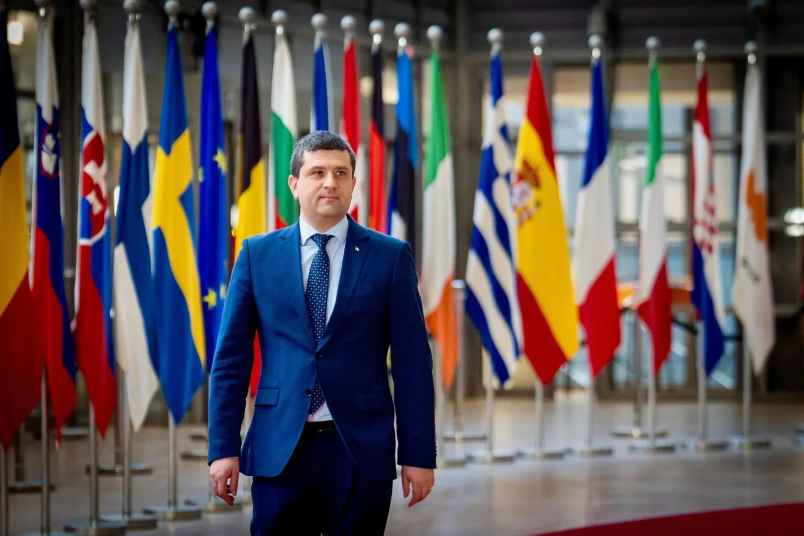 Oficial în fața steagurilor țărilor membre NATO, la o întâlnire importantă.