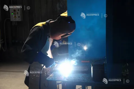 Un tehnician efectuează lucrări de sudură într-un mediu industrial.