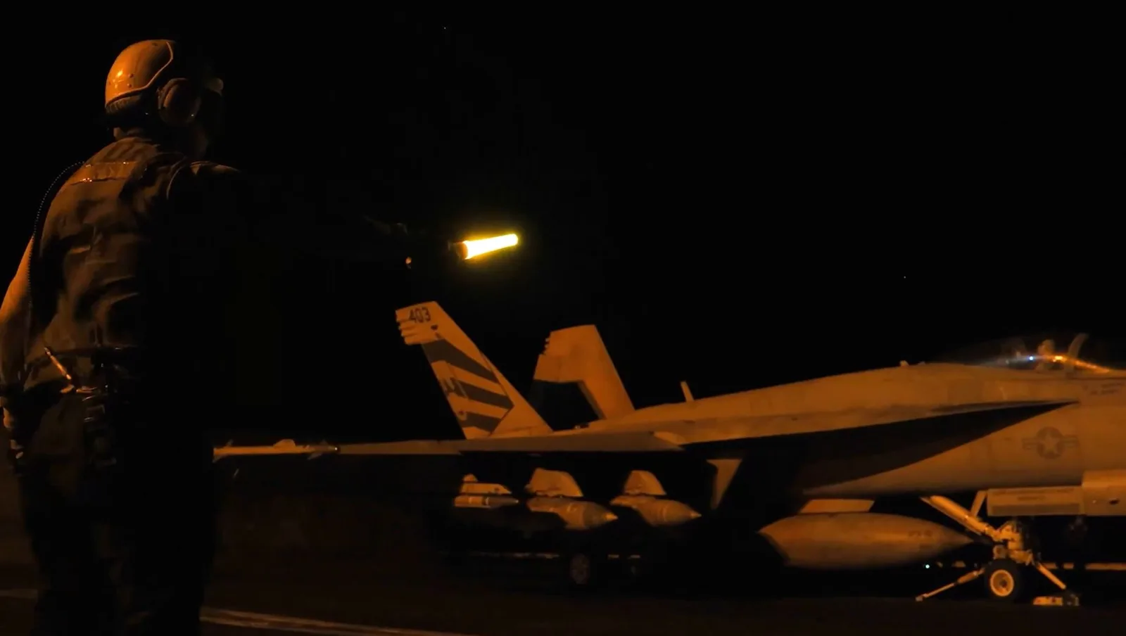 Un militar dirijează avioane pe timp de noapte, în contextul tensiunilor internaționale.