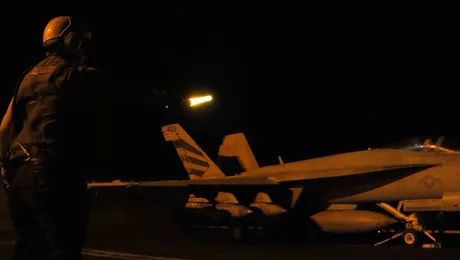 Un militar dirijează avioane pe timp de noapte, în contextul tensiunilor internaționale.