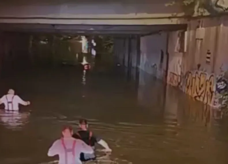 Pompieri înotând în apă pentru a verifica mașinile scufundate în București.