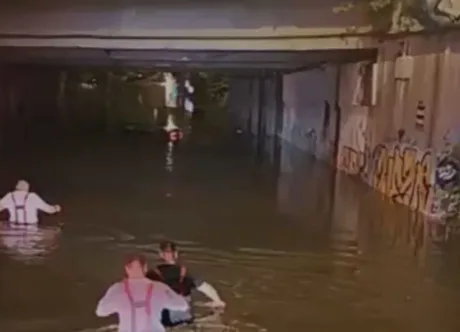 Pompieri înotând în apă pentru a verifica mașinile scufundate în București.