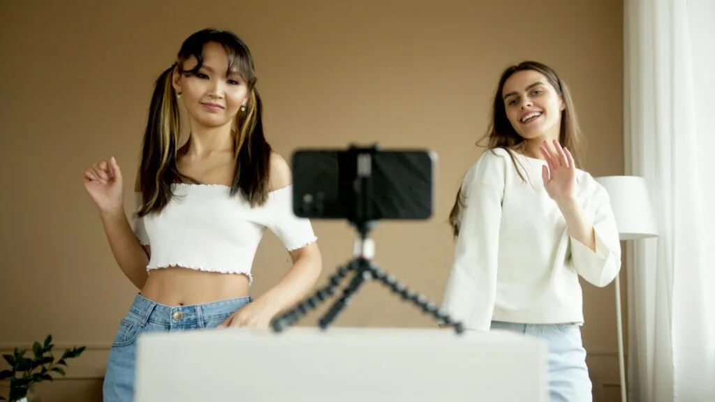 Două creatoare de conținut dansează în fața unei camere video.