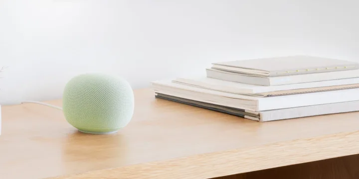 Difuzor inteligent pe o masă, cărți și un decor minimalist.