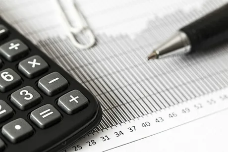 Calculatoare și grafice financiare pe un birou, simbolizând analiza economică.