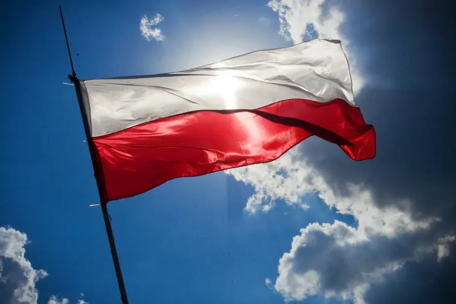 Steagul Poloniei fluturând sub soare pe un fundal albastru.