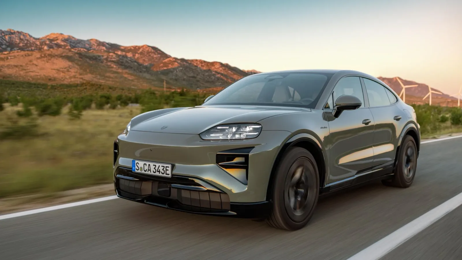 Porsche Cayenne Electric pe drum, în peisaj montan la apus.