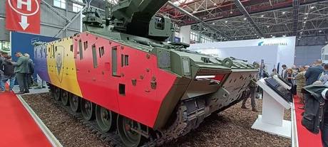 Vehicul militar cu steagul României expus la un târg de apărare.