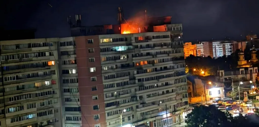 Incendiu pe un bloc de locuințe în timpul nopții, cu lumini strălucitoare.