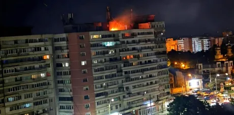 Incendiu pe un bloc de locuințe în timpul nopții, cu lumini strălucitoare.