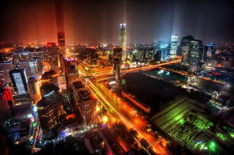 Peisaj urban nocturn din Beijing, cu lumini strălucitoare și clădiri moderne.