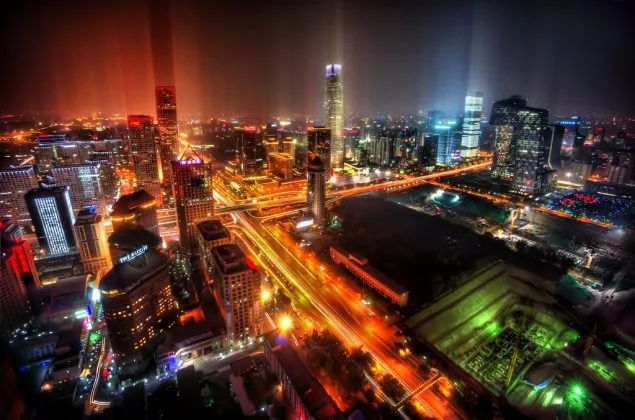 Peisaj urban nocturn din Beijing, cu lumini strălucitoare și clădiri moderne.
