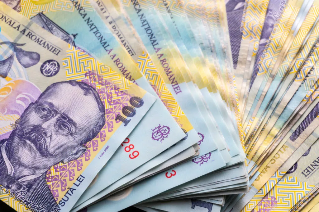 Bancnote de lei aranjate pe o suprafață, simbolizând economisirea.
