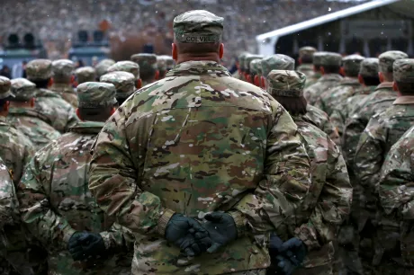 Soldați în uniformă, ascultând un discurs militar.